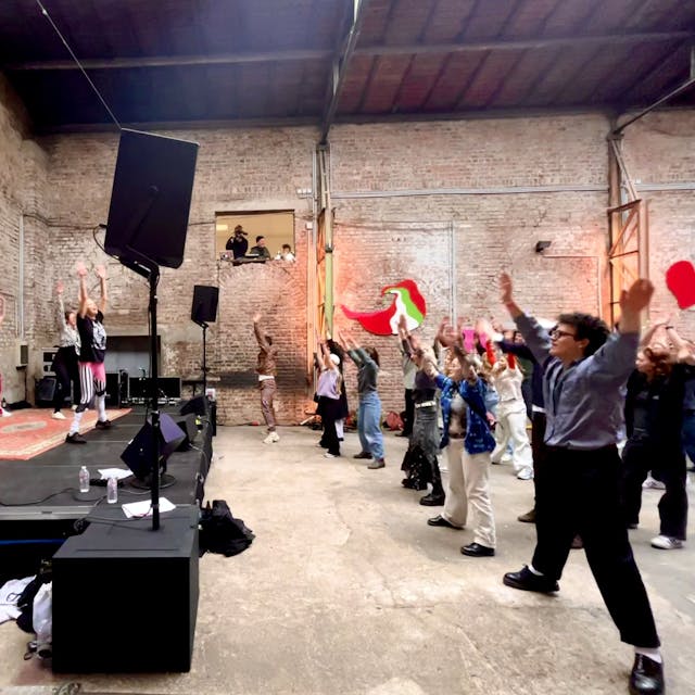 Besucher des Neue Wellen Festival tanzen in einer der alten Hallen vor einer Bühne.