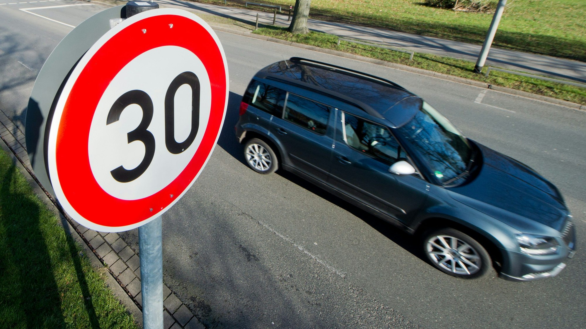 Das Bild zeigt ein Tempo 30-Schild, an dem ein Auto vorbeifährt.