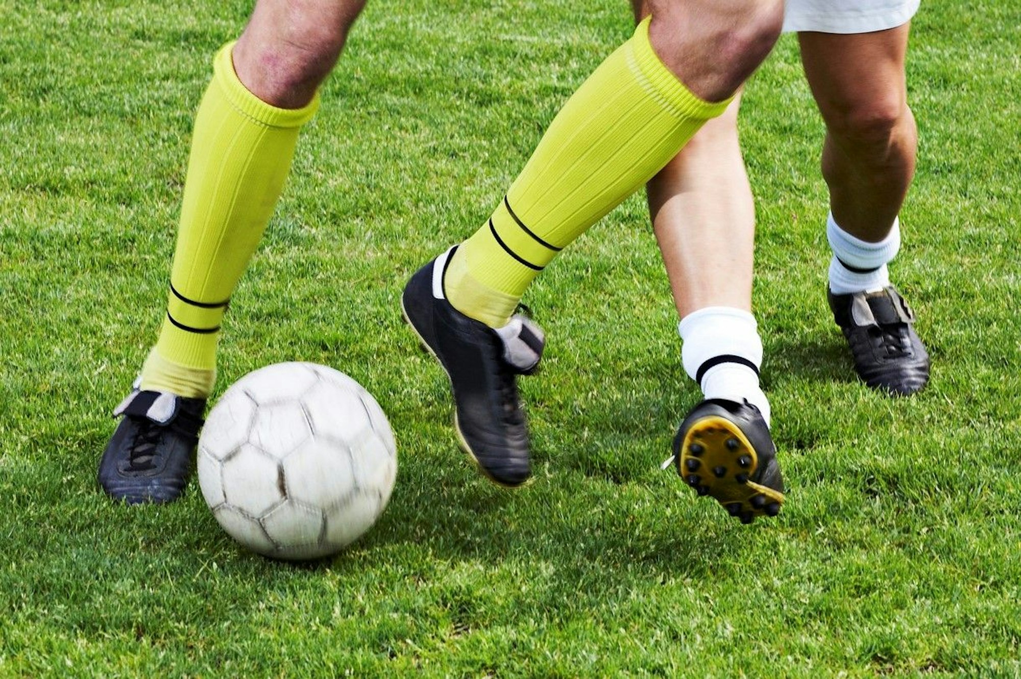 Die Beine von zwei Fußballspielern, die um den Ball kämpfen.