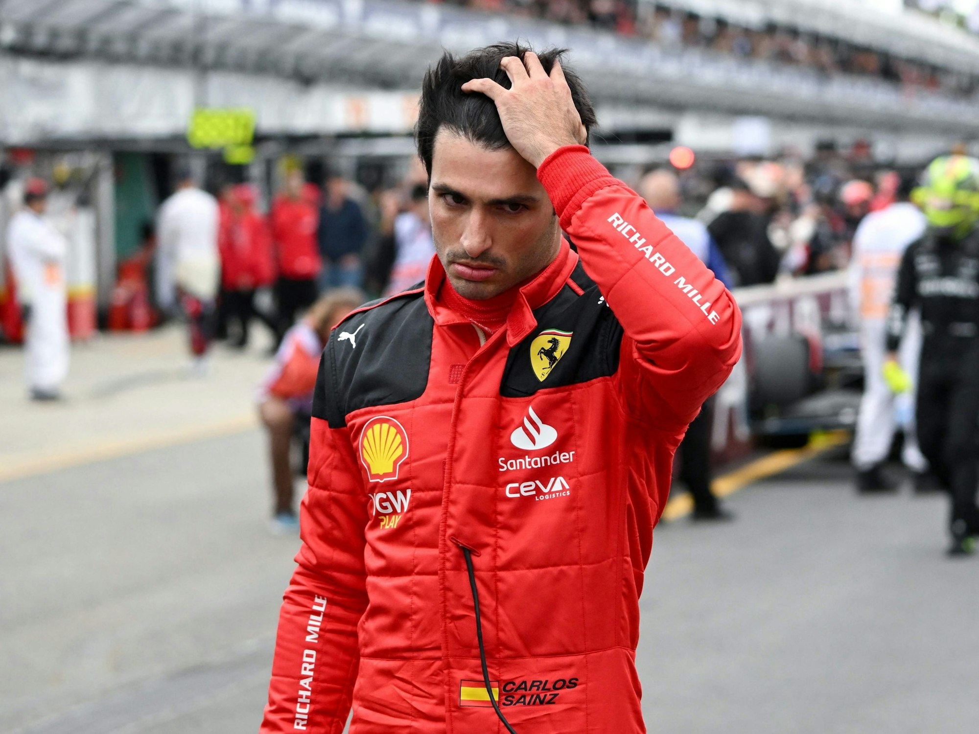 Ferrari-Pilot Carlos Sainz Jr streicht sich durchs Haar.