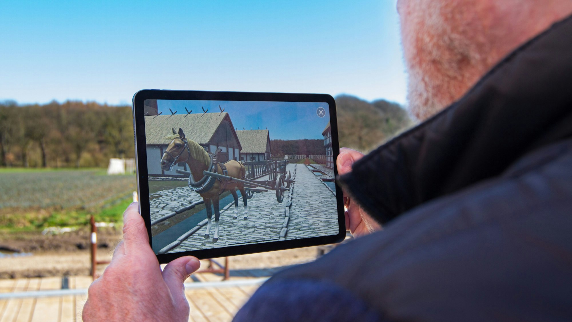 Ein Mann kann auf einem iPad entdecken, wie die Archäologische Stätte Corvey im Mittelalter ausgesehen hat.