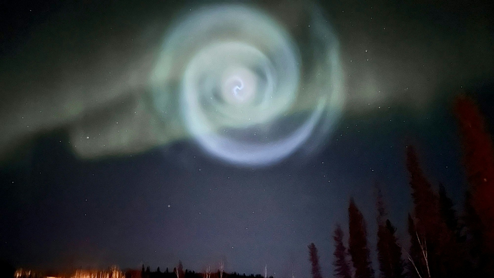 Eine hellblaue Spirale, die wie eine Galaxie aussieht, ist am Samstag zwischen Nordlichtern für ein paar Minuten am Himmel in Alaska zu sehen gewesen.