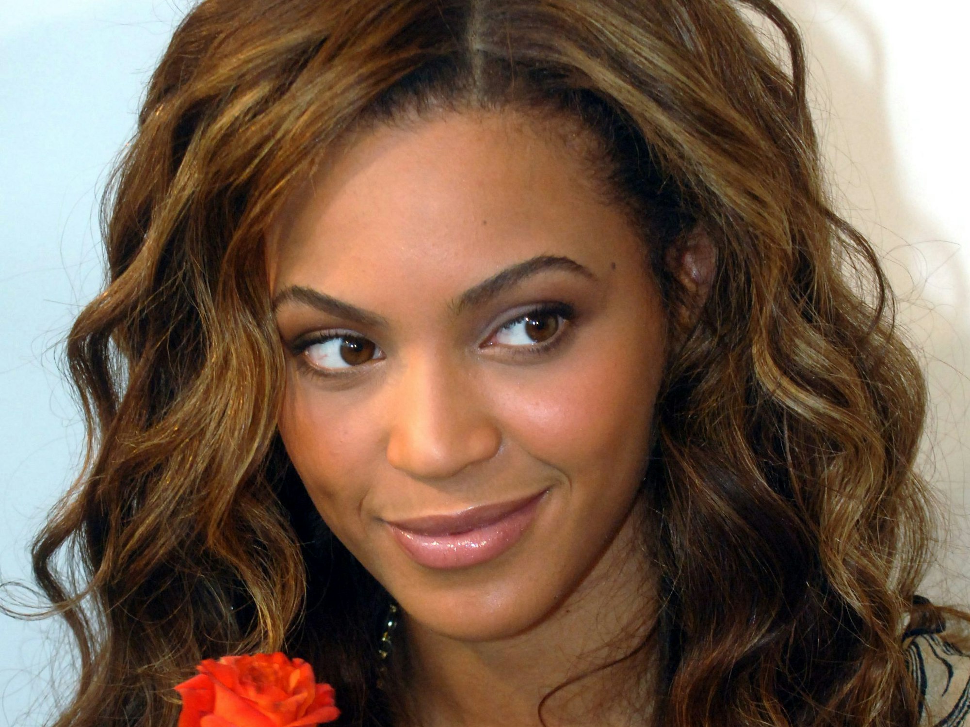 Beyoncé hält eine Blume in der Hand und lächelt