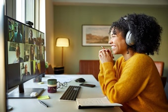 Businesswoman with headphones smiling during video conference. Multiracial male and female professionals are attending online meeting. They are discussing business strategy.