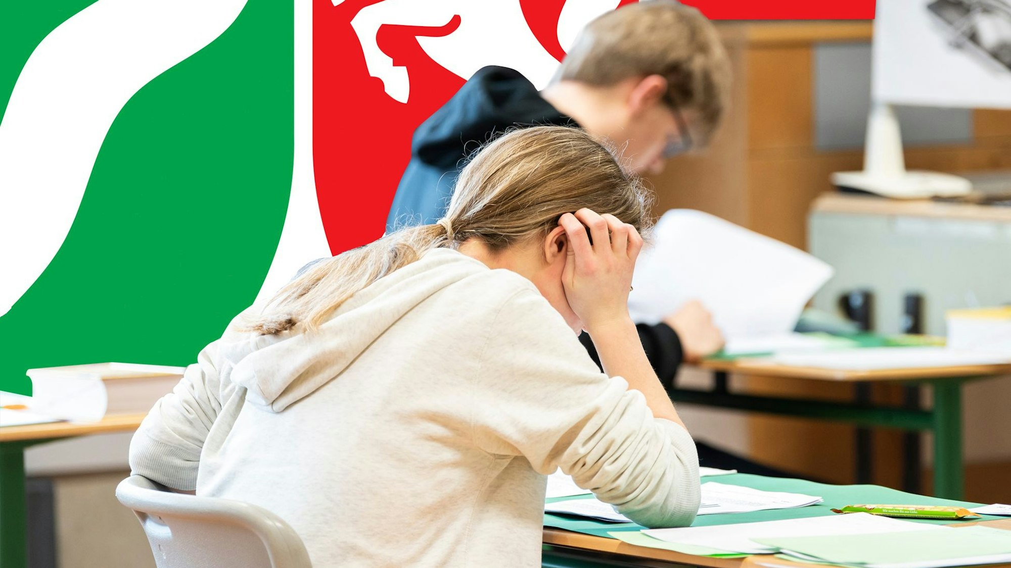 Schüler beugen sich über Prüfungsaufgaben. Im Hintergrund hängt eine NRW-Flagge.