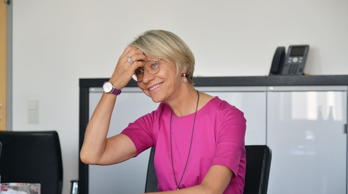 Dorothee Feller (CDU), Bildungsministerin in Nordrhein-Westfalen, sitzt in einem Büro und lächelt.