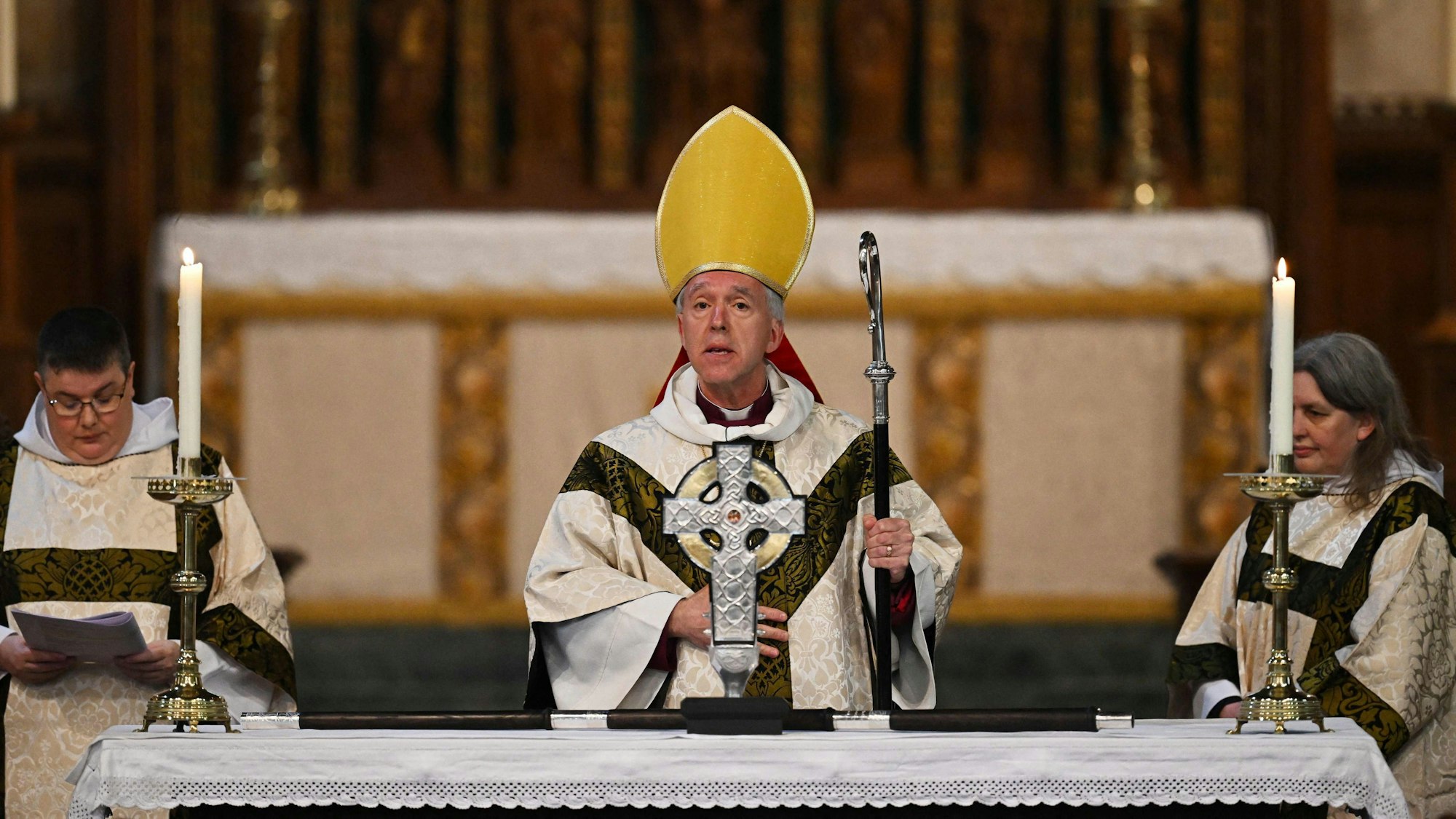 Andrew John, Erzbischof von Wales, steht hinter dem „Cross of Wales“ zusammen mit zwei anderen kirchlichen Dienern.