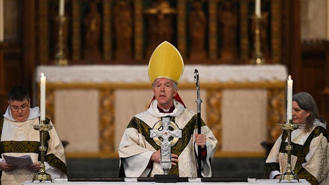 Andrew John, Erzbischof von Wales, steht hinter dem „Cross of Wales“ zusammen mit zwei anderen kirchlichen Dienern.