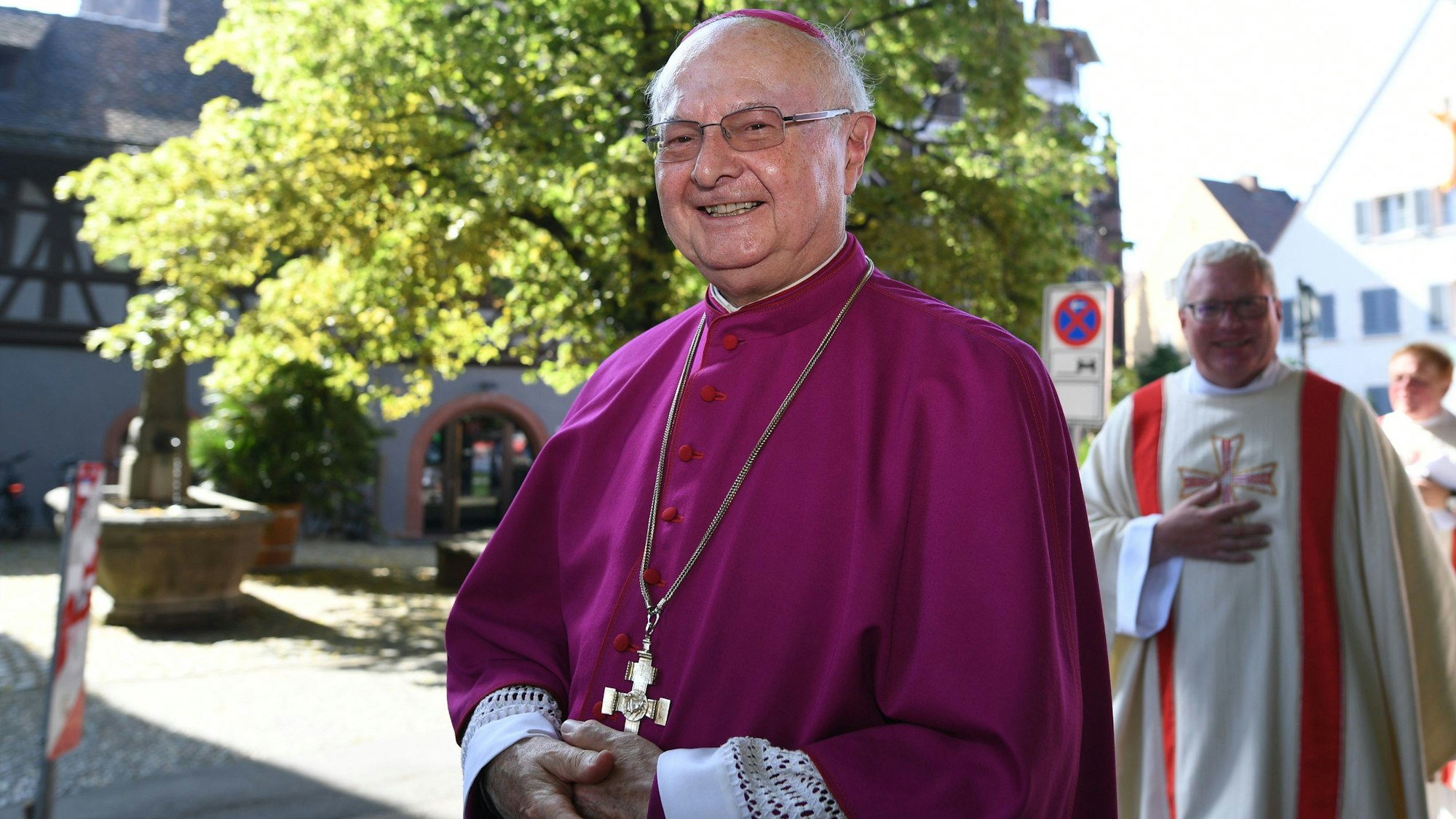 Der ehemalige Freiburger Erzbischof Robert Zollitsch steht vor einem Baum.