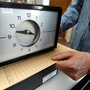 Eine Karte zur Arbeitszeiterfassung wird in einem Betrieb unter eine Stechuhr gelegt.