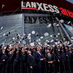 Polizeianwärter werfen ihre Mützen vor der Lanxess Arena in die Luft.&nbsp;