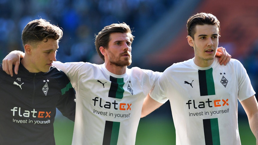 Jonas Hofmann (M.) feiert am 9. April 2023 den Sieg von Borussia Mönchengladbach gegen den VfL Wolfsburg mit Jan Olschowsky (l.) und Florian Neuhaus. Das Gladbach-Trio steht Arm in Arm vor der Nordkurve.