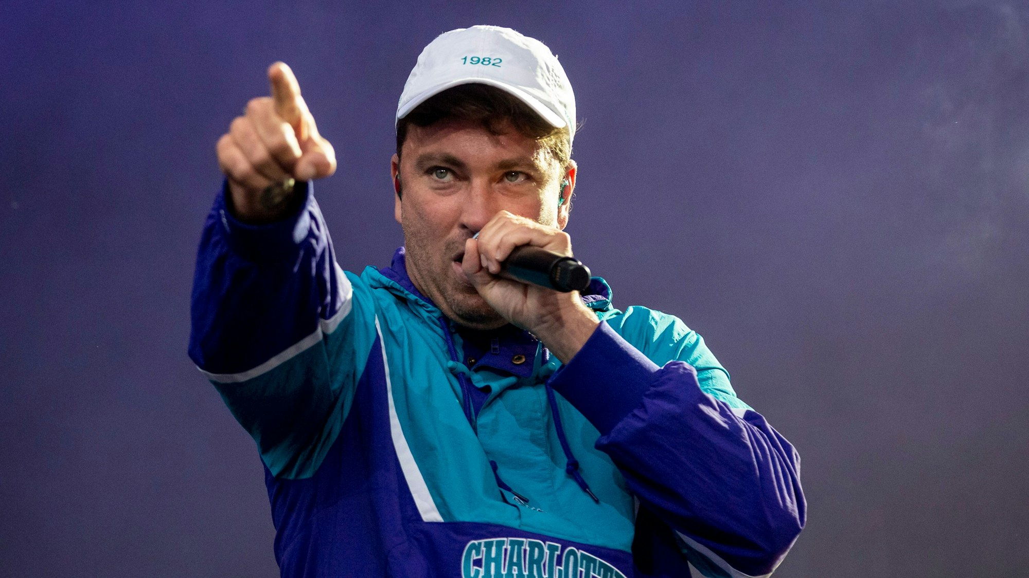 Der deutsche Rapper Marteria (40) bei einem Auftritt auf einer Bühne. Er trägt eine Kappe und hält ein Mikrofon in der Hand.