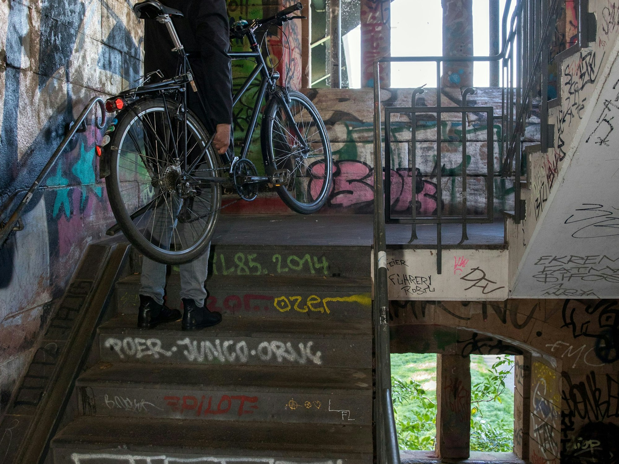 Ein Mann trägt sein Fahrrad im Aufgang zur Südbrücke.
