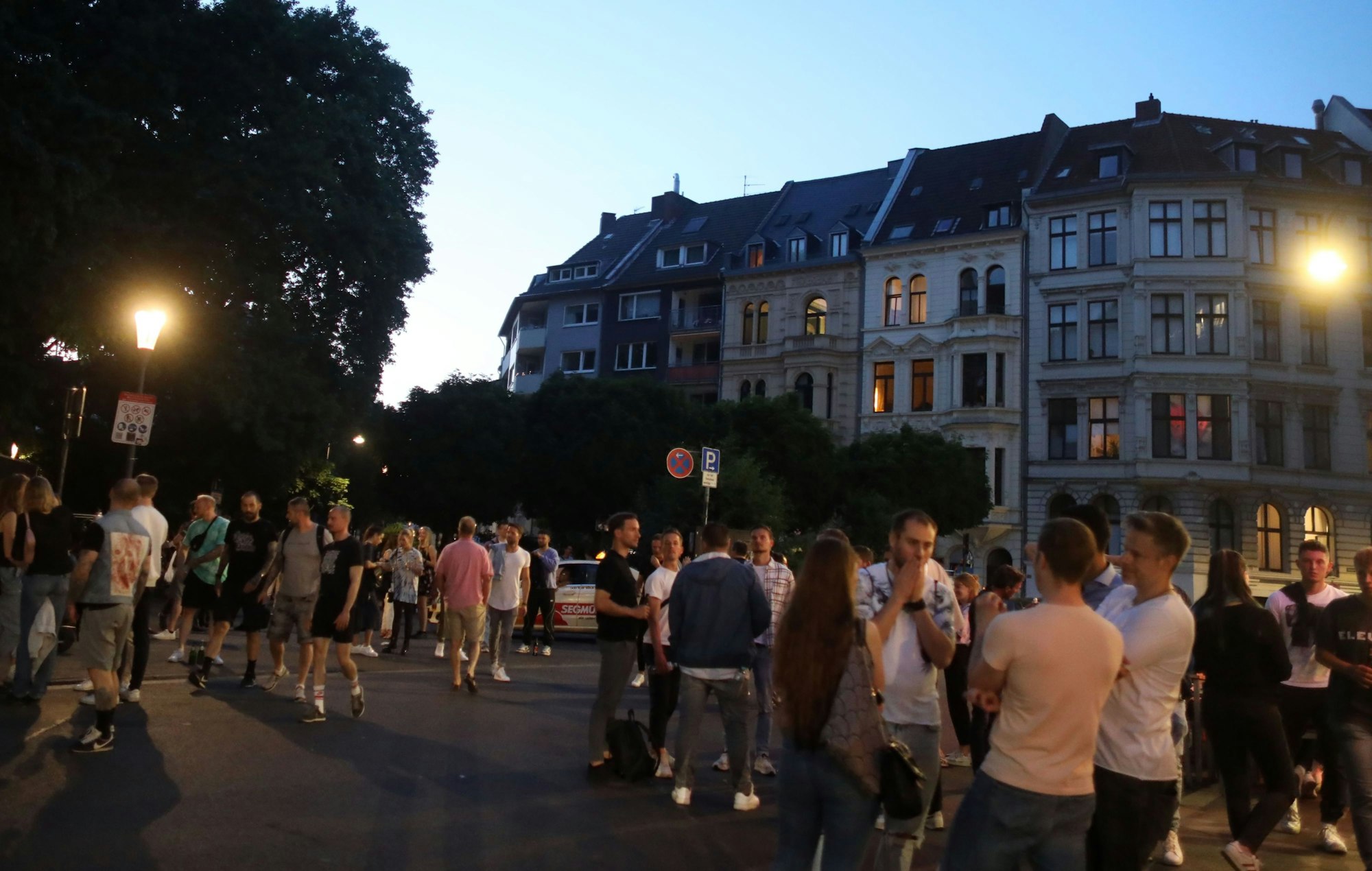Menschen stehen an einem Sommerabend am Brüsseler Platz.