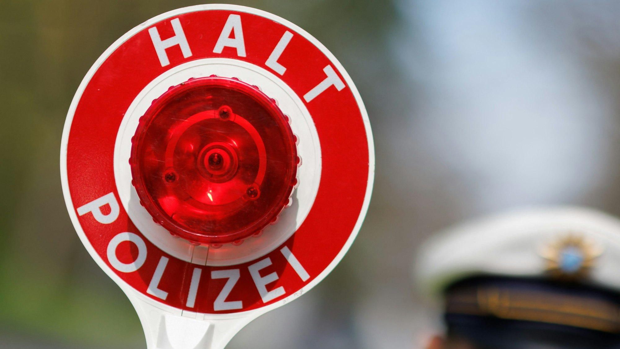 21.04.2023, Bayern, Nürnberg: Ein Polizist zieht ein Fahrzeug mit seiner Kelle aus dem Verkehr.