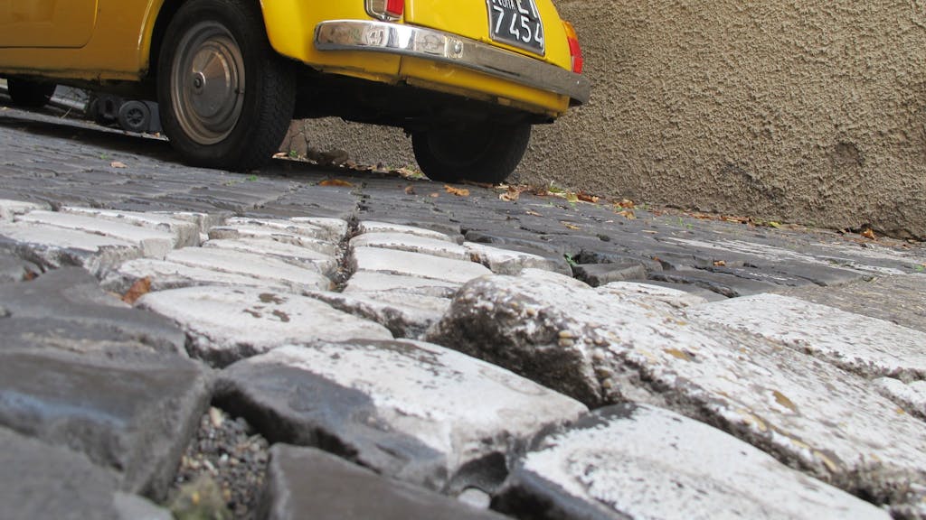 Teilweise lose Pflastersteine im Kopfsteinpflaster in einer Gasse in der italienischen Hauptstadt Rom.