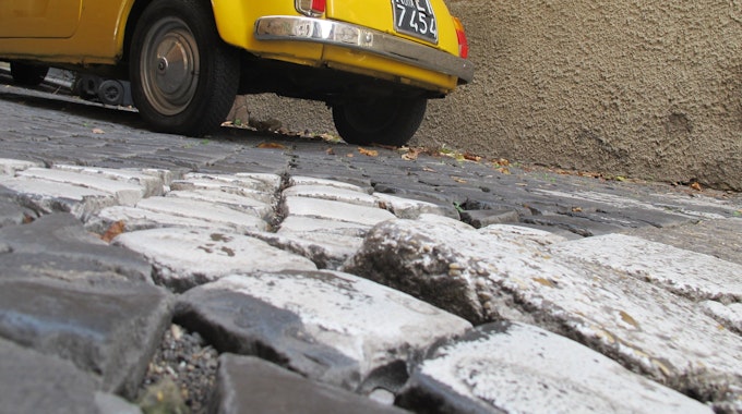 Teilweise lose Pflastersteine im Kopfsteinpflaster in einer Gasse in der italienischen Hauptstadt Rom.