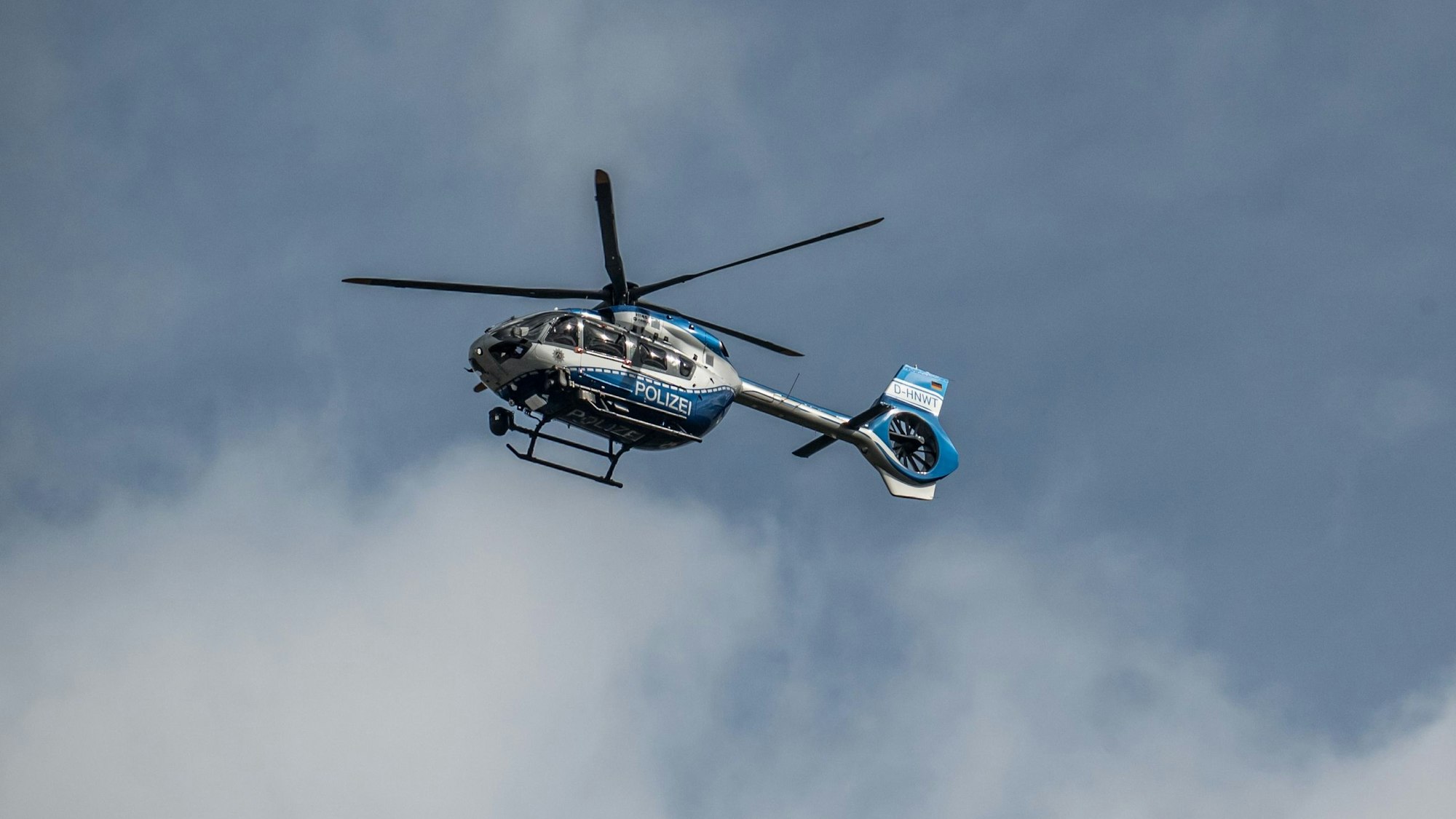 Ein Polizeihubschrauber mit fünfblättrigen Rotor fliegt über Leverkusen.