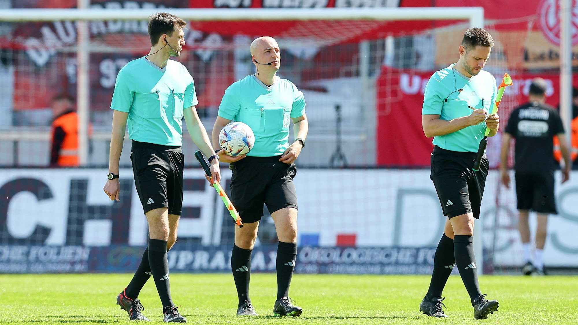 Schiedsrichter-Assistent Felix Grund, Schiedsrichter Nicolas Winter und Schiedsrichter-Assistent Fabian Porsch stehen auf dem Feld.