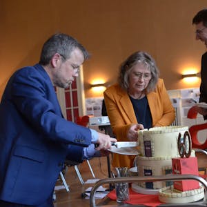 Die Vorstände Martin Jost (v.l.) und Maria Surges-Brilon schneiden die  Geburtstagstorte an, Kreisdechant Guido Zimmermann assistiert.  
