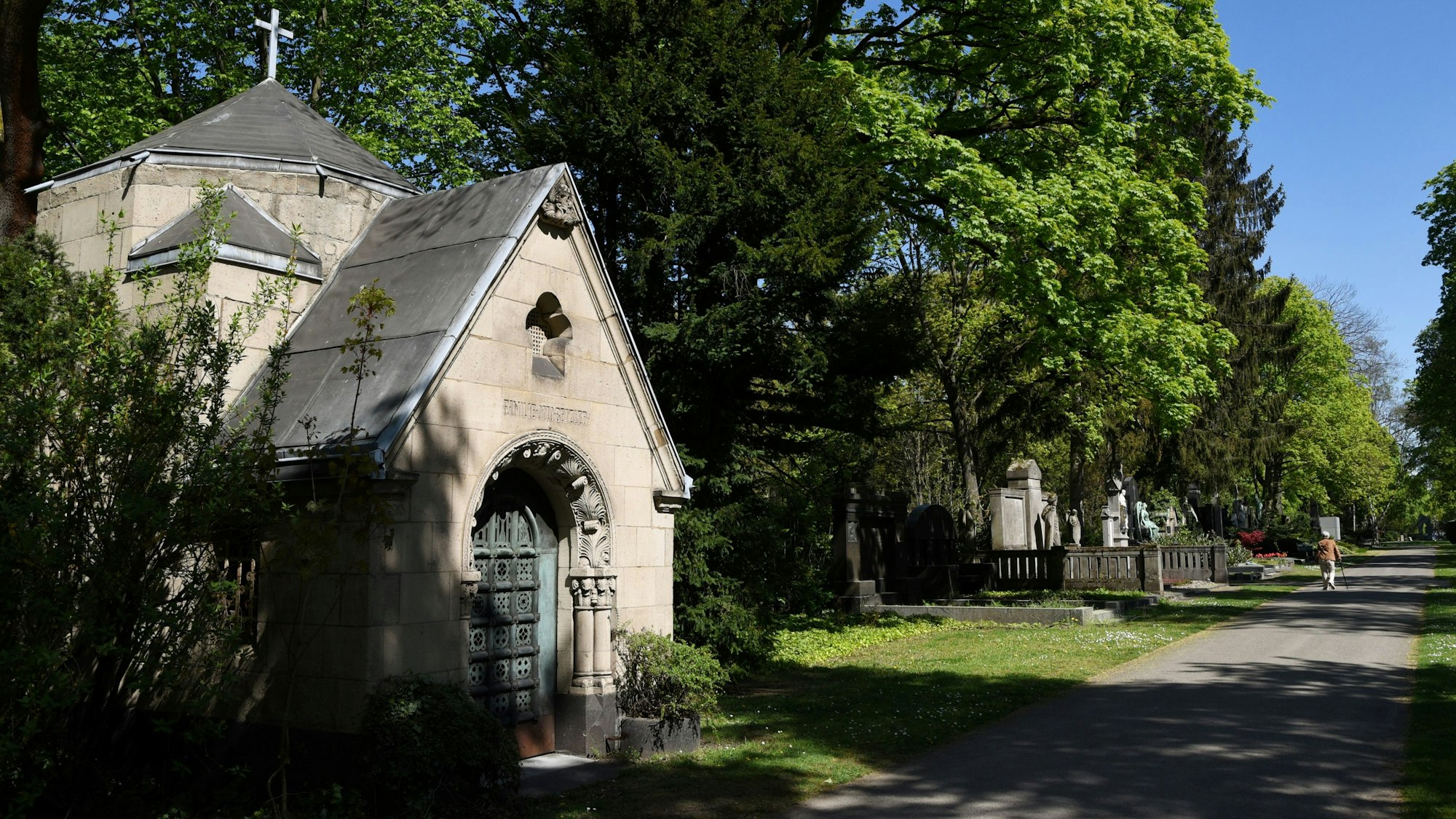 Der Melatenfriedhof in Köln mit einer Gruft und grünen Bäumen