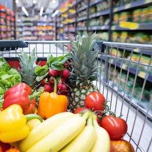 Ein Einkaufskorb mit Obst und Gemüse steht in einem Supermarkt. Der kräftige Anstieg der Lebensmittelpreise in den vergangenen Monaten ist nach Einschätzung des Kreditversicherers Allianz-Trade nicht nur auf die gestiegenen Rohstoffkosten und Energiepreise zurückzuführen.