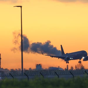 Ein Airbus der Luftwaffe fliegt vor einem goldenen Morgenhimmel den Flughafen BER in Berlin an.