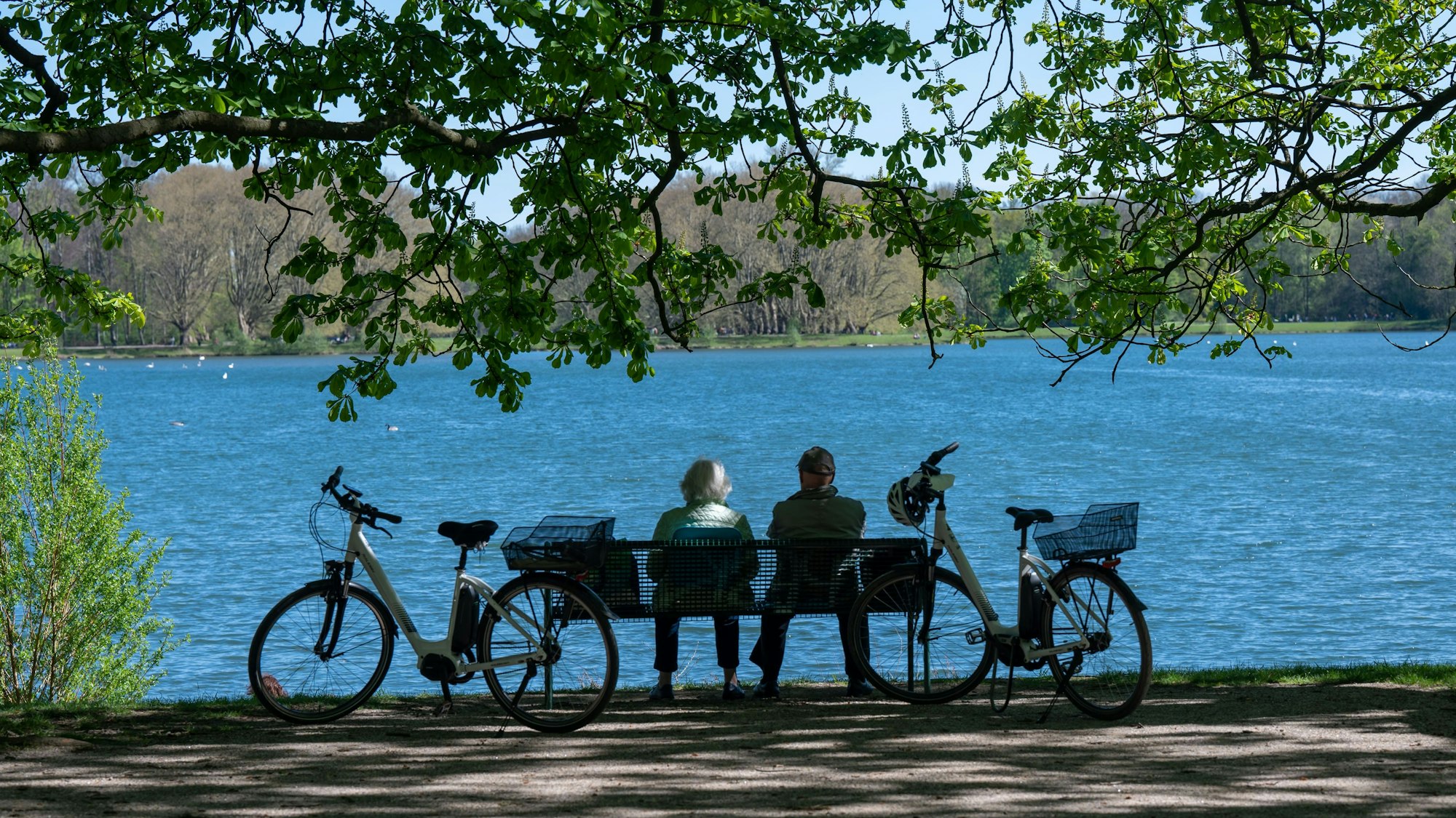 Ein Paar sitzt auf einer Bank mit Blick auf den Decksteiner See in Köln