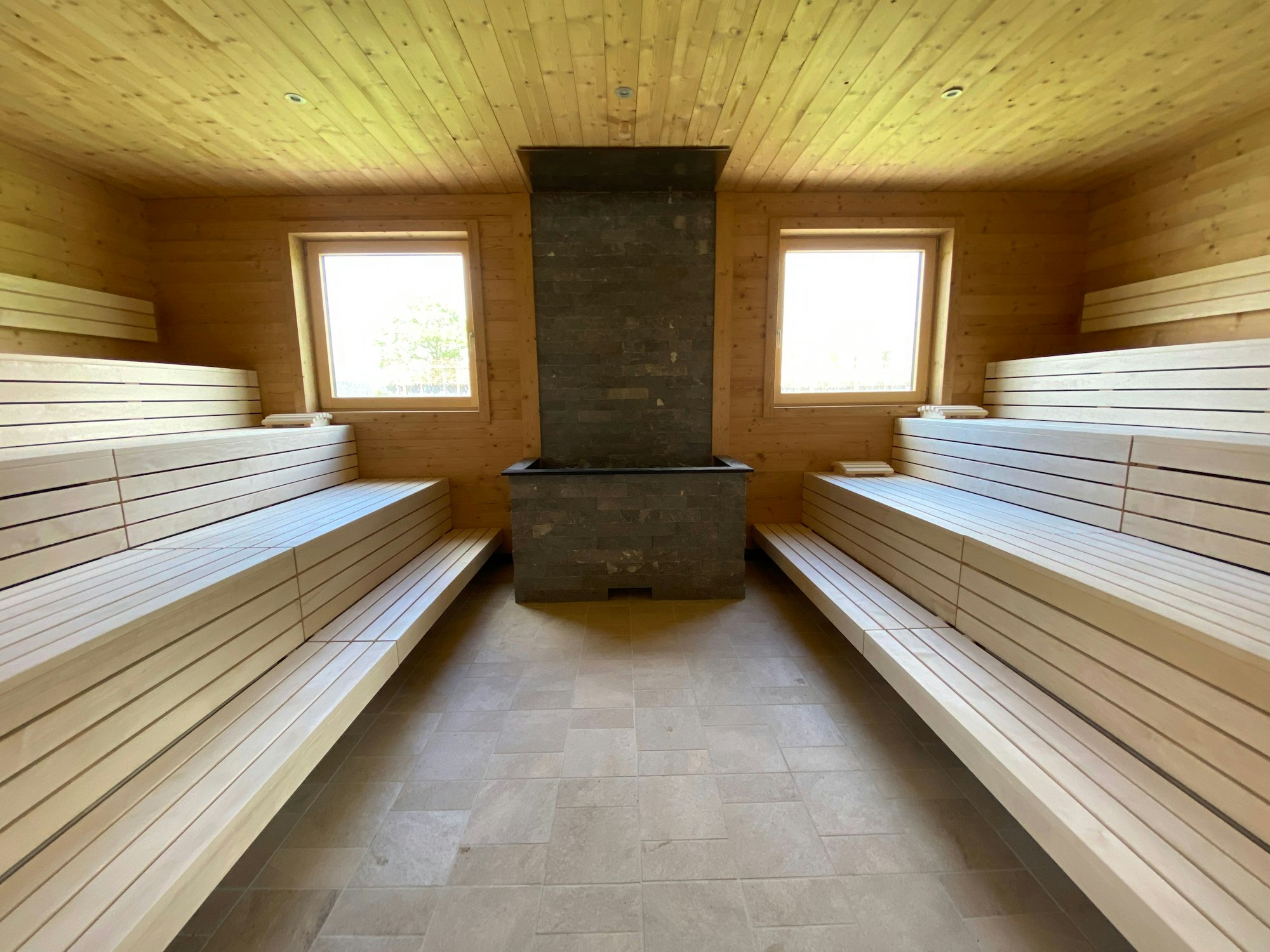 Eine Sauna mit Holzbänken und zwei Fenstern mit Blick nach draußen.