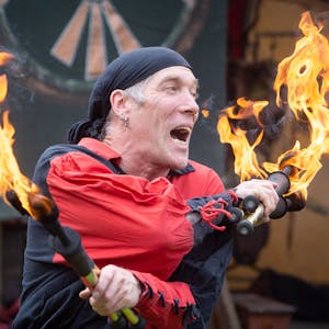 Ein Künstler jongliert mit zwei brennenden Fackeln.