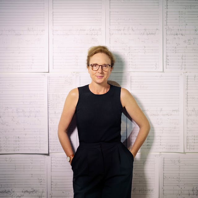 Die Britische Komponistin Rebecca Saunders. Sie steht vor einer Wand, in der große Zettel mit Noten hängen.&nbsp;