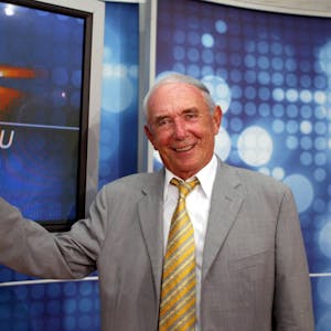 Das Bild zeigt Ex-Sportschau Moderator Ernst Huberty, vor dem Logo der Sportschau.