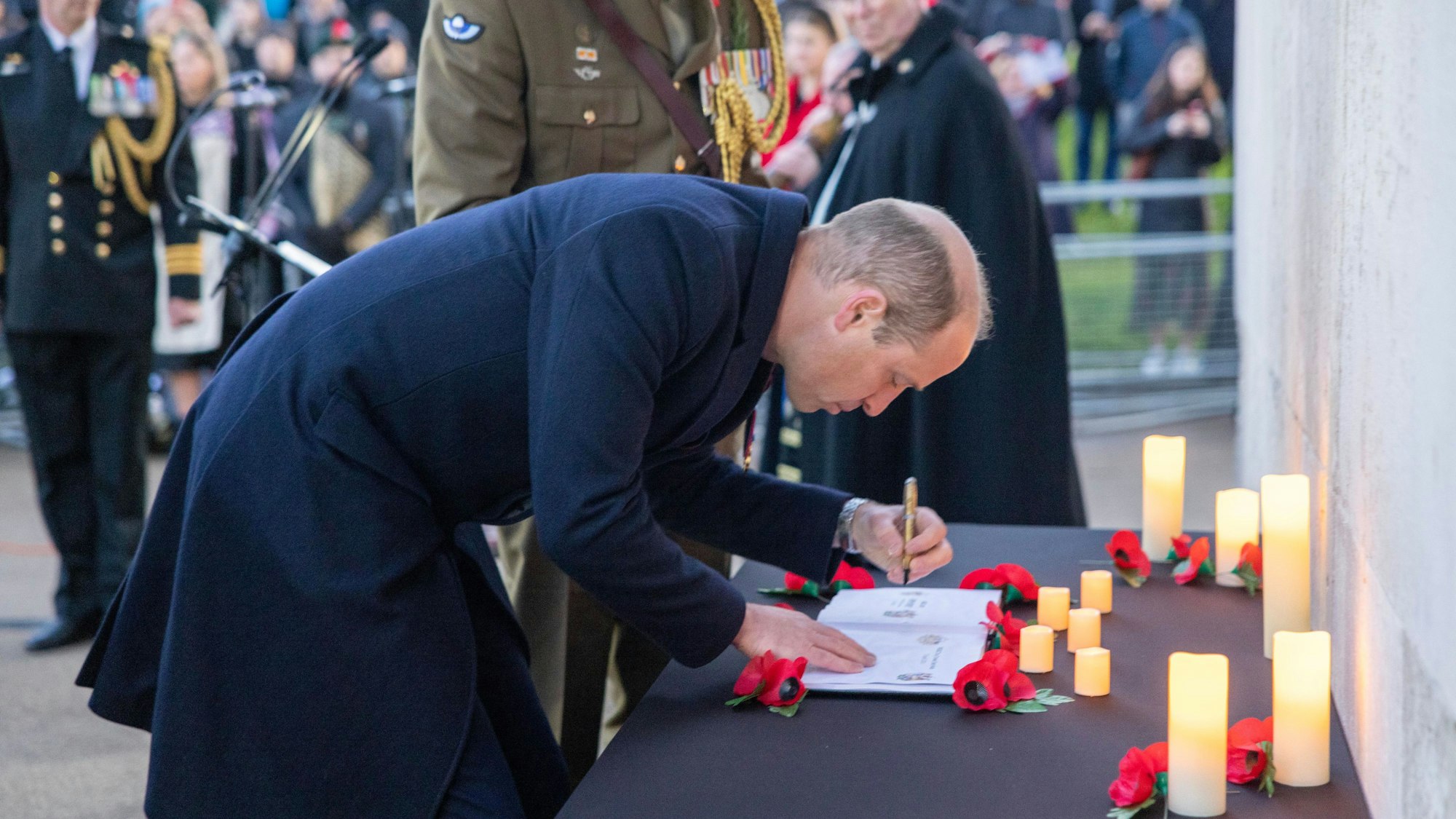 Prinz William, Prinz von Wales, nimmt an der Morgenandacht zum Anzac Day 2023 teil. Er schreibt sich in ein Gedenkbuch ein. Es brennen Kerzen vor ihm.