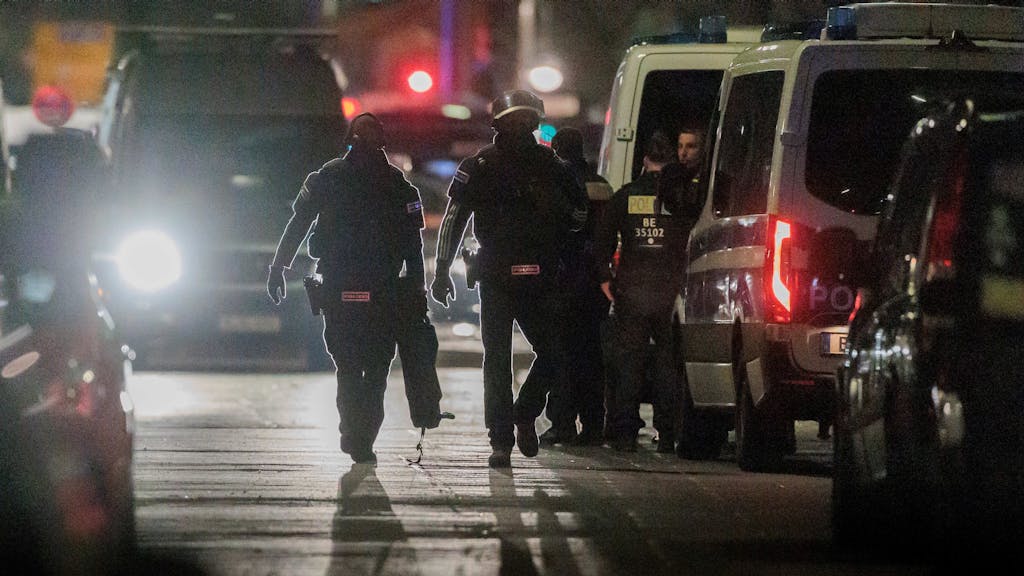 Polizisten gehen zu den Einsatzfahrzeugen nach der Beendigung einer Geiselnahme in einem Geschäft an der Keithstraße.