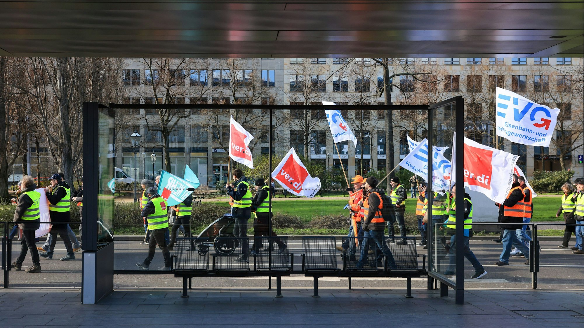 Mitglieder von Verdi und der Eisenbahn- und Verkehrsgewerkschaft EVG ziehen in einer Demonstration hinter einer leeren Straßenbahnhaltestelle vorbei.