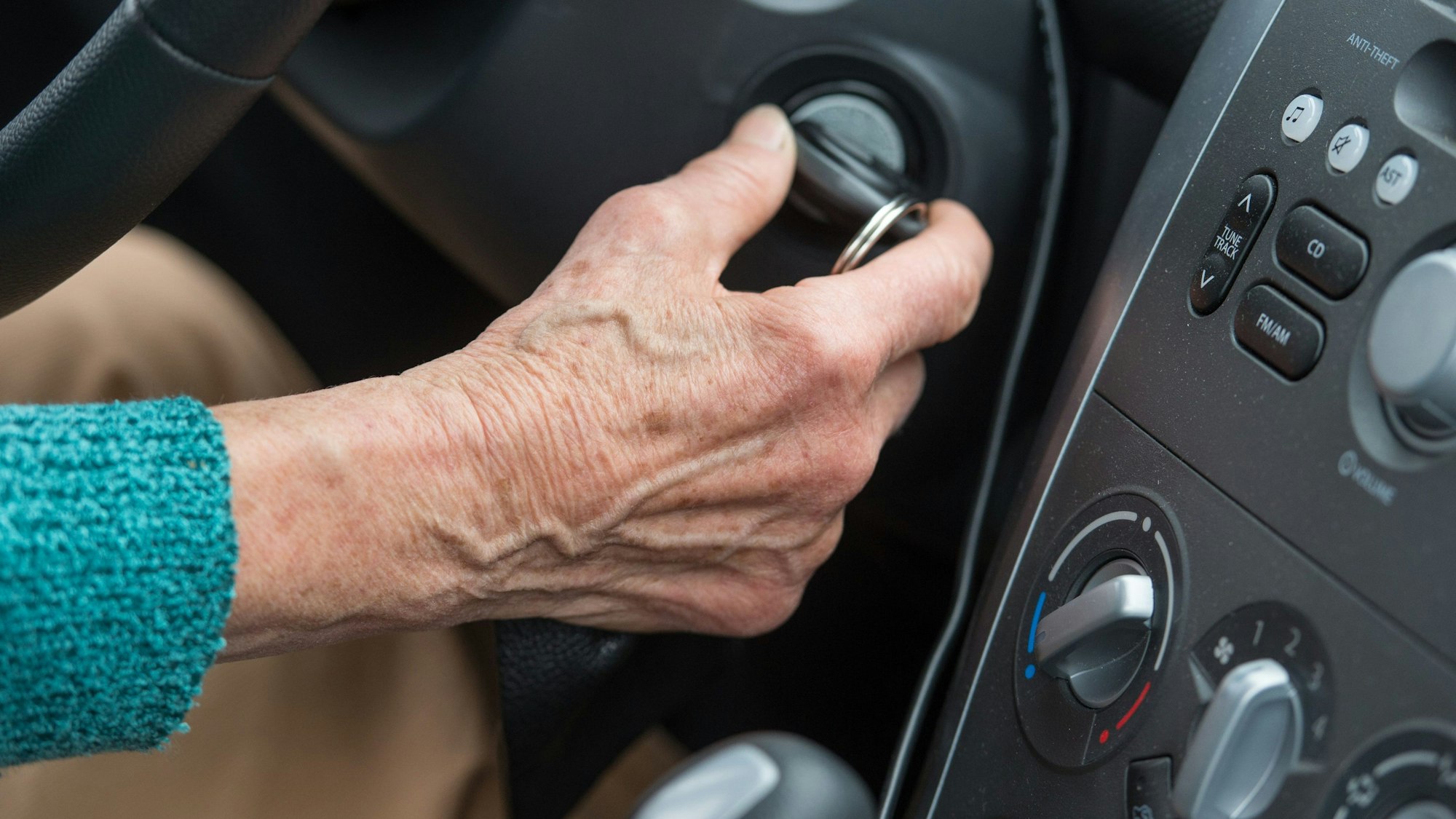 Eine Rentnerin startet mit dem Zündschlüssel ihr Auto.