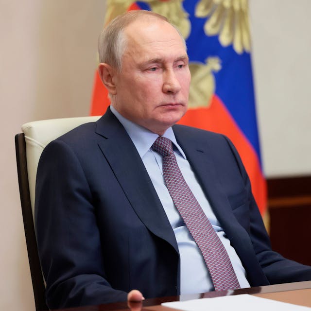 Der russische Präsident Putin sitzt auf einem Stuhl. Hinter ihm steht eine Flagge.&nbsp;