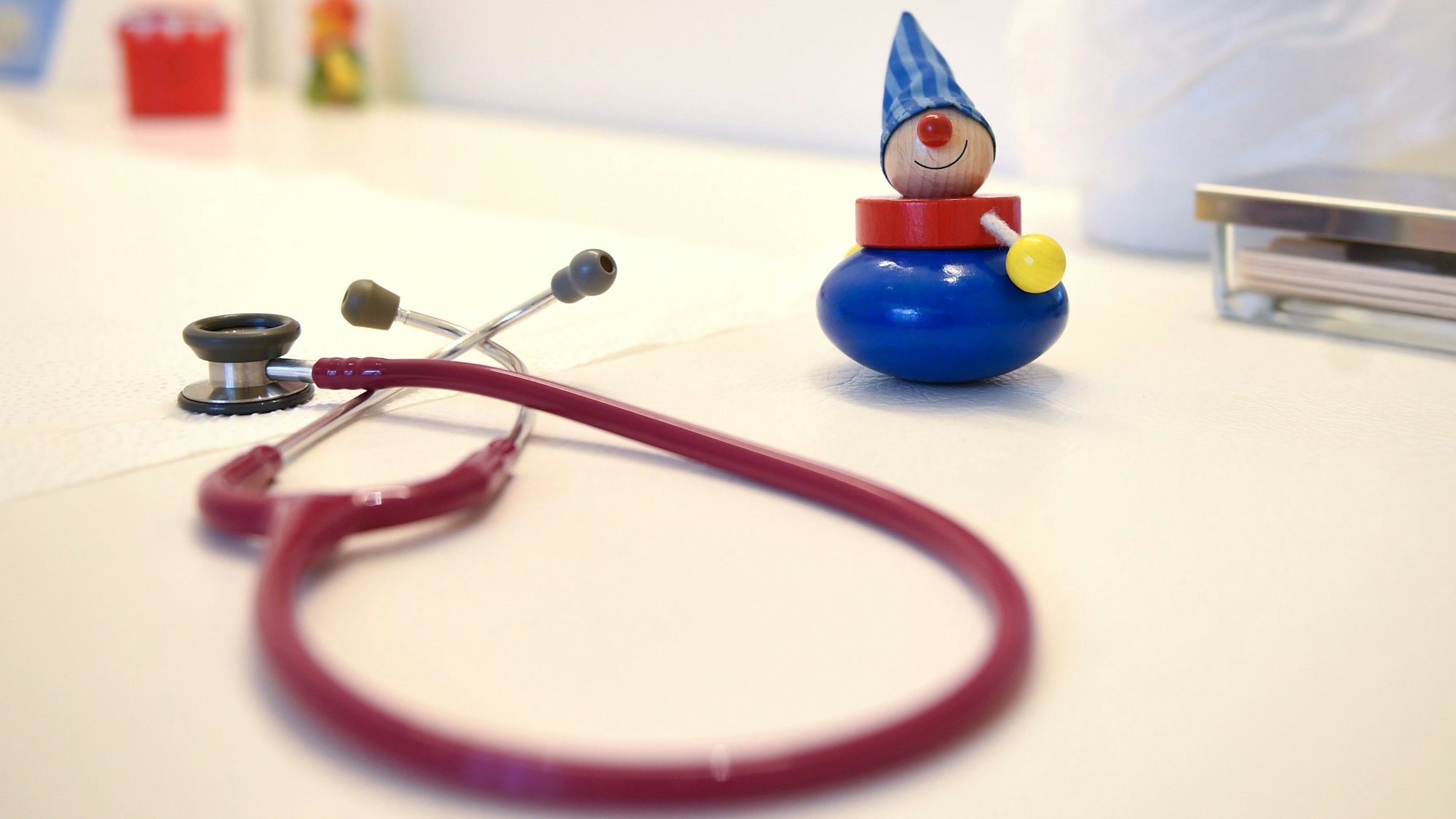 Ein Stethoskop und Kinderspielzeug liegen in einer Kinderarztpraxis auf einem Tisch. (Symbolbild)