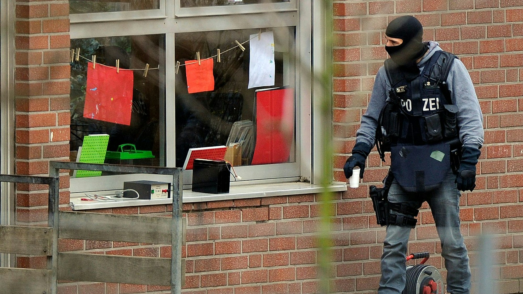 Ein Beamter eines Spezialeinsatzkommandos (SEK) der Polizei blickt am durch ein Fenster in eine Kindertagesstätte, in der es zu einer Geiselnahme gekommen ist.