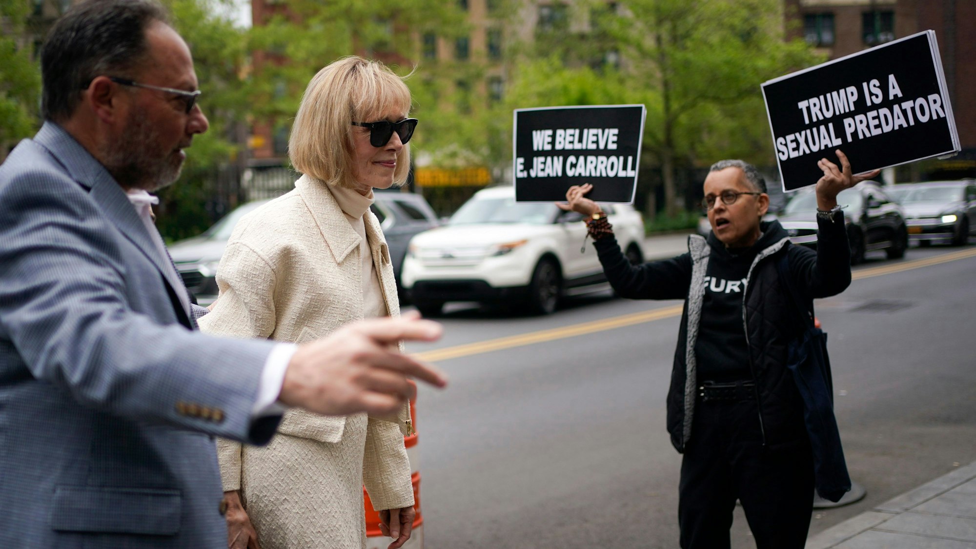 Während ein Demonstrant zwei Schilder hochhält, trifft E. Jean Carroll (M) vor dem Bundesgericht ein. Die US-Autorin Carroll wirft Donald Trump vor, er habe sie Mitte der 1990er Jahre in einem New Yorker Kaufhaus vergewaltigt.