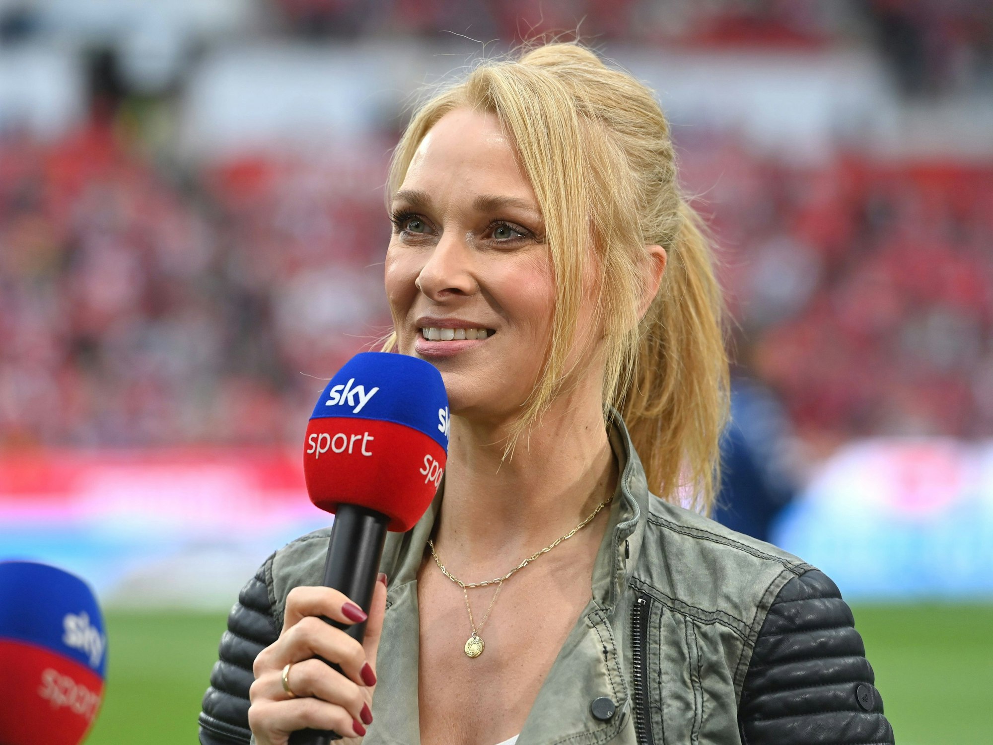Sky-Moderatorin Britta Hofmann hält ein Mikrofon in der Hand.