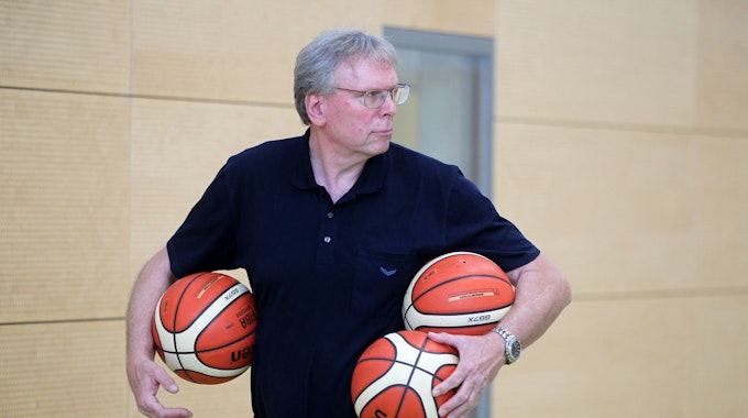 Manager Frank Beier trägt drei Basketbälle unter den Armen.