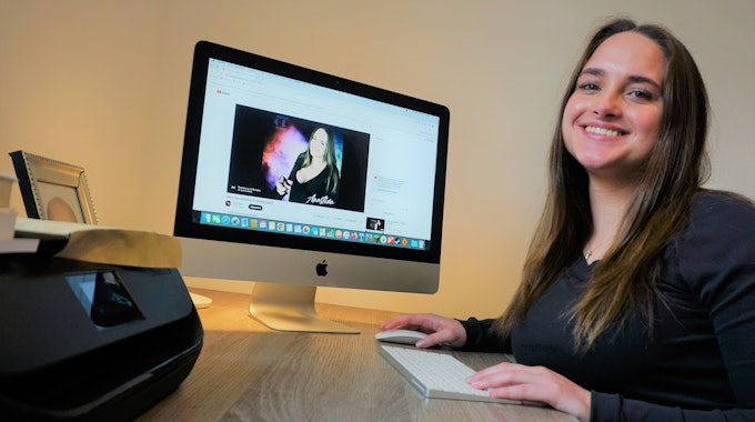 Schlagersängerin Anastida präsentiert ihre Debüt-Single. Im Hintergrund ist sie selbst auf einem Mac-PC in einem YouTube-Video abgebildet.