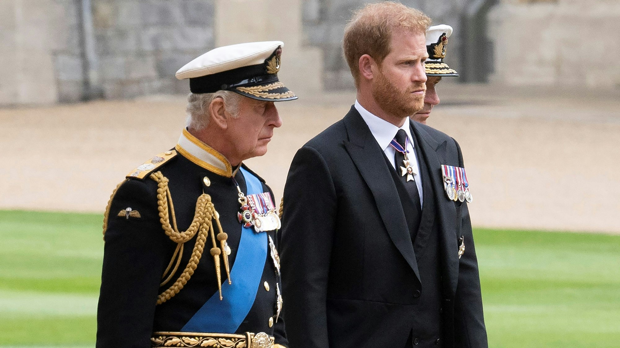 König Charles III. und Prinz Harry gehen auf einem Weg nebeneinander.