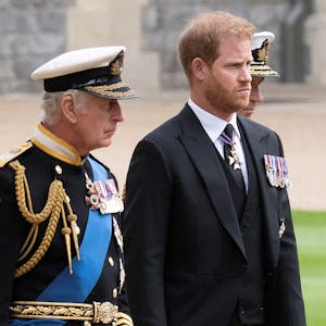 König Charles III. und Prinz Harry gehen auf einem Weg nebeneinander.