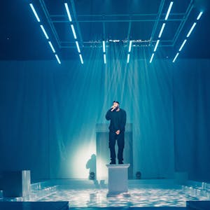 Rapper OG Keemo steht auf einer weißen Säule im Bühnenbild von "Die Troerinnen" im Depot 1 des Schauspiels Köln.&nbsp;