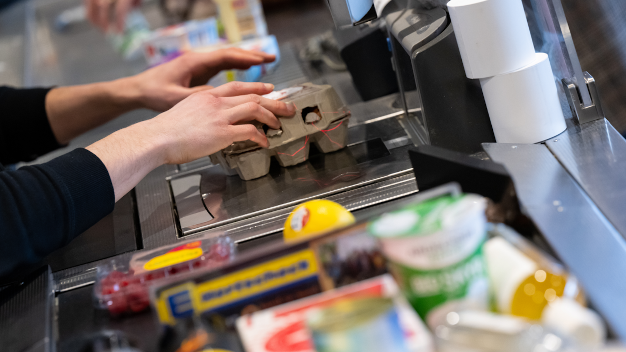 Ein Kassierer scannt in einem Supermarkt an der Kasse die Produkte.