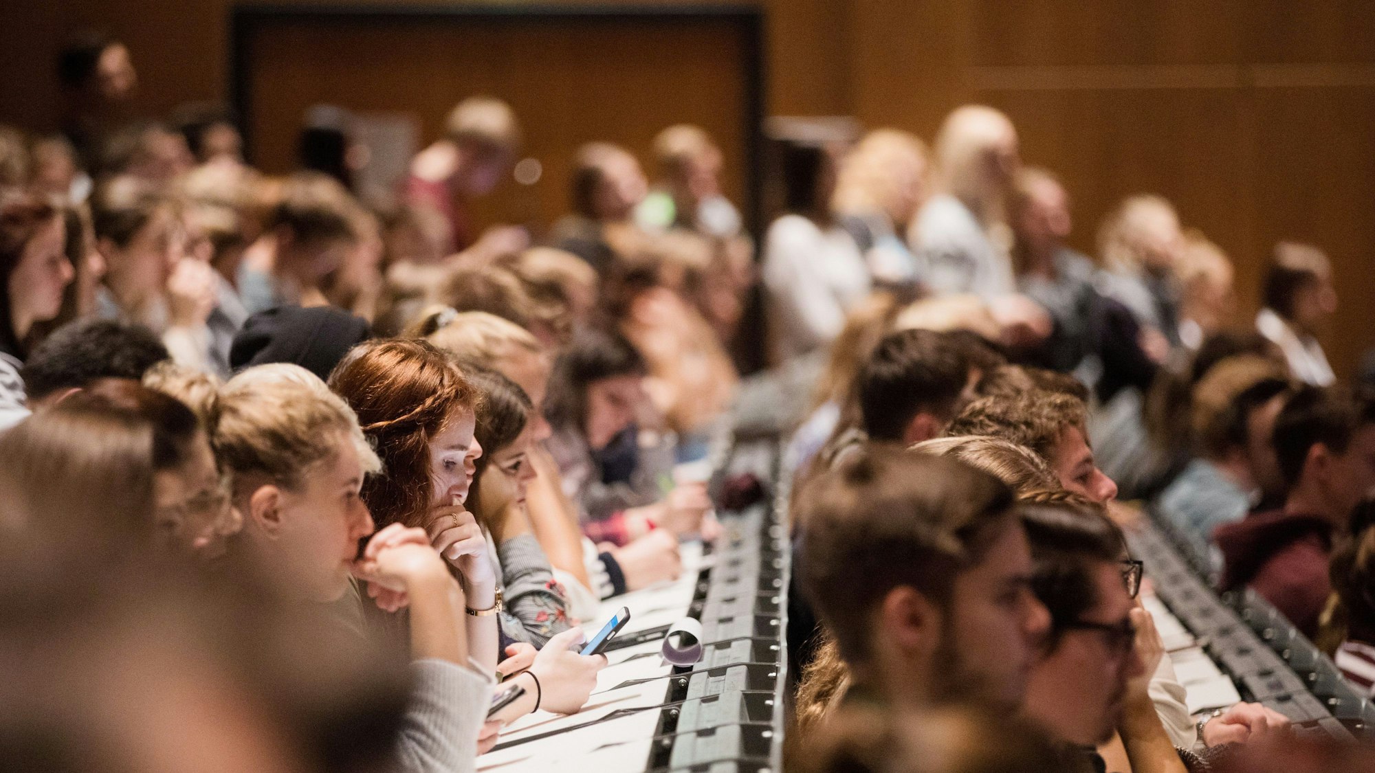 Studenten und Studentinnen verfolgen sitzen in einem Hörsaal.
