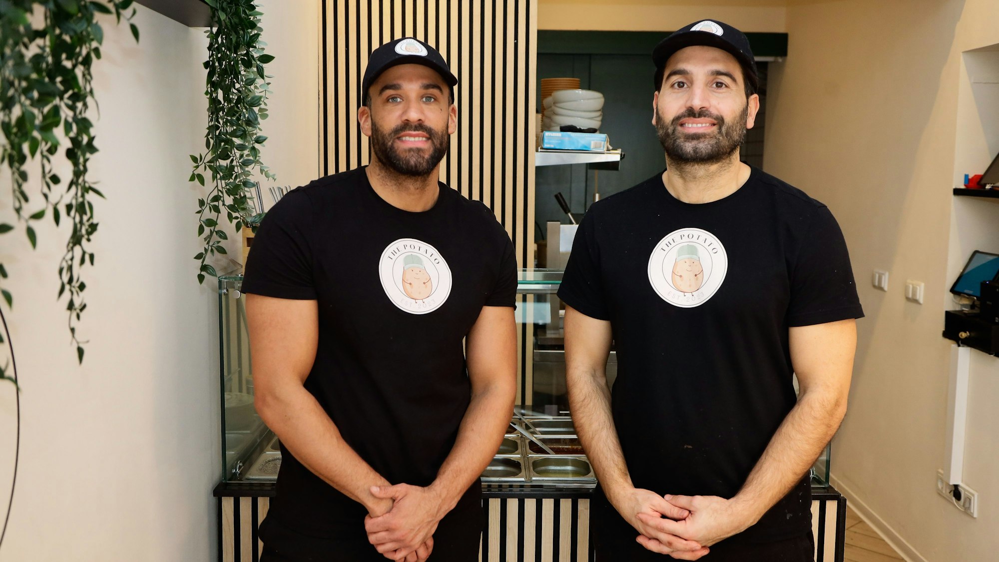 Zwei Männer stehen in einem Laden, sie tragen schwarze Shirts mit Logo.